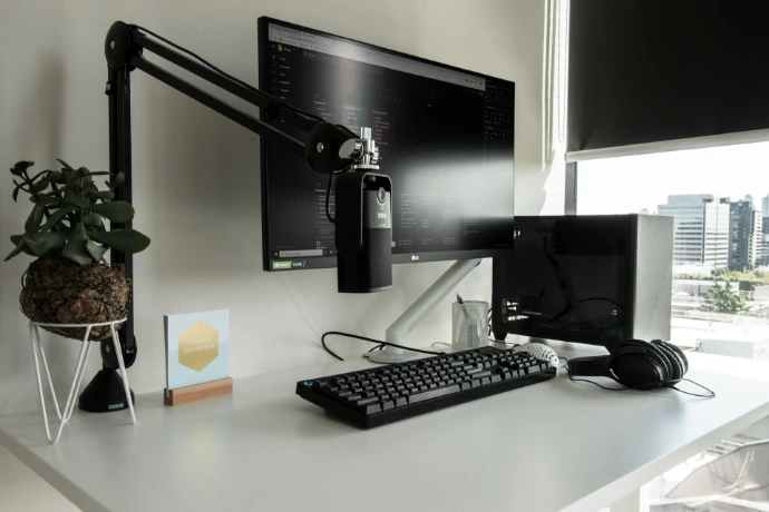 a desk with a computer monitor, keyboard and mouse